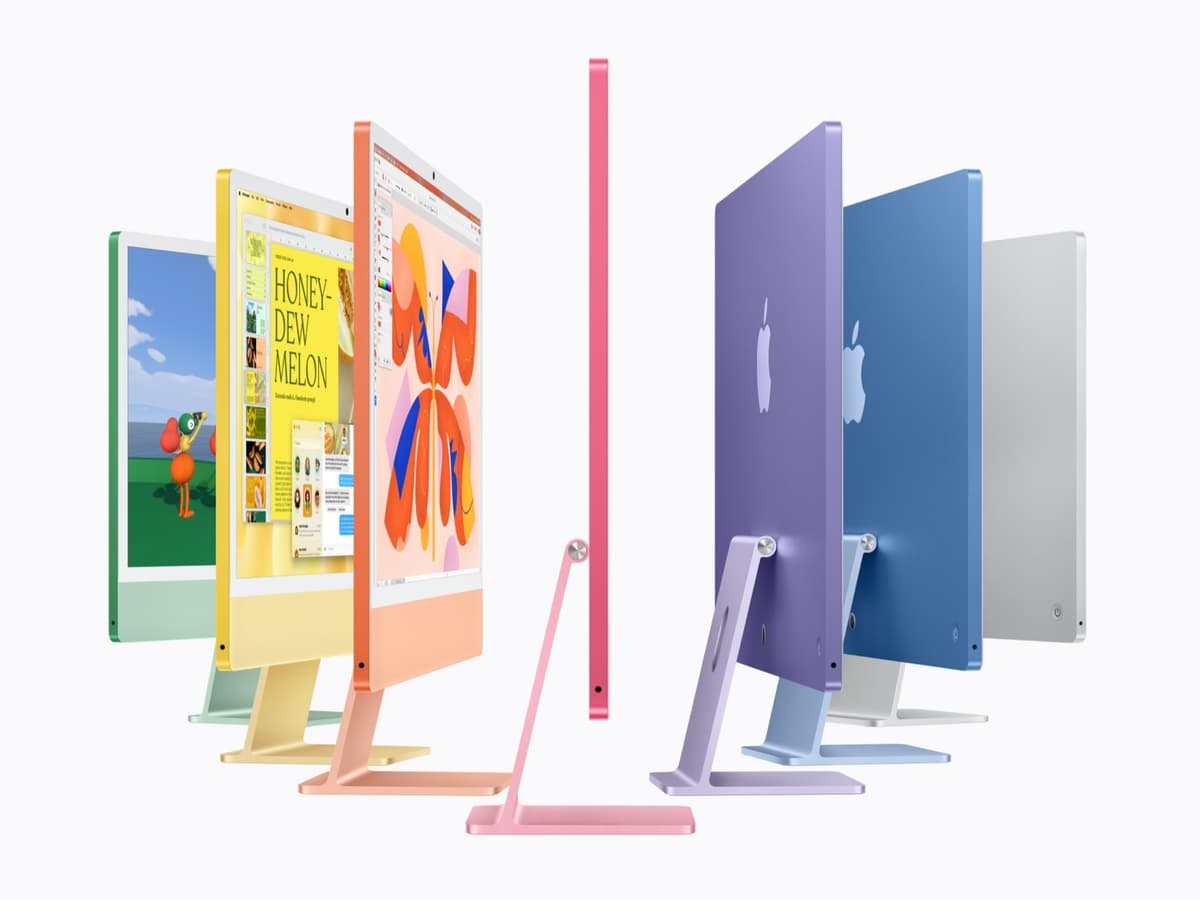 שבעה מחשבי iMac חדשים בצבעים ירוק, צהוב, כתום, ורוד, סגול, כחול וכסוף, מסודרים בחצי עיגול