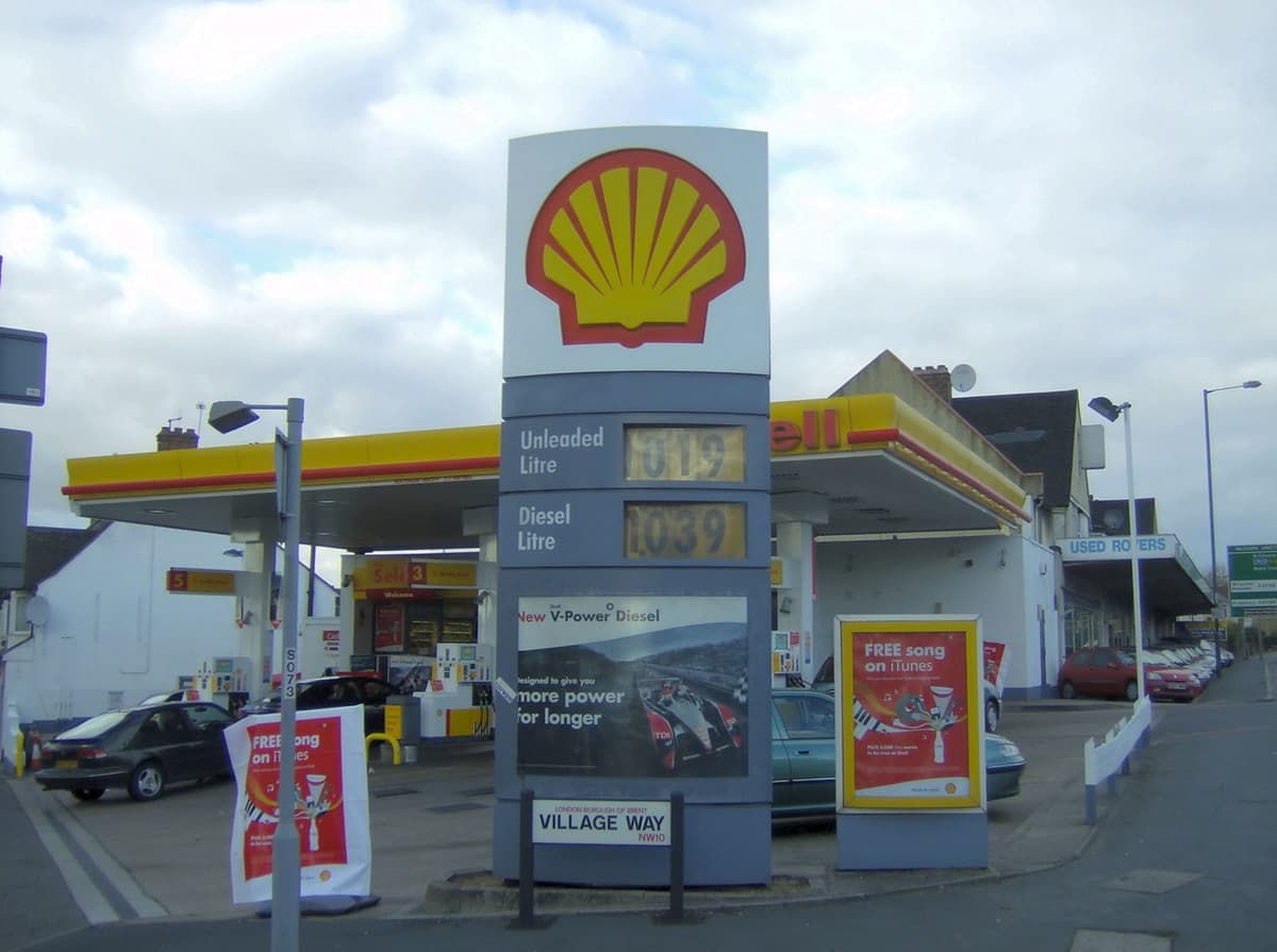 שלט הצדפה הצהובה של Shell מעל עמוד מחירי דלק בתחנת דלק